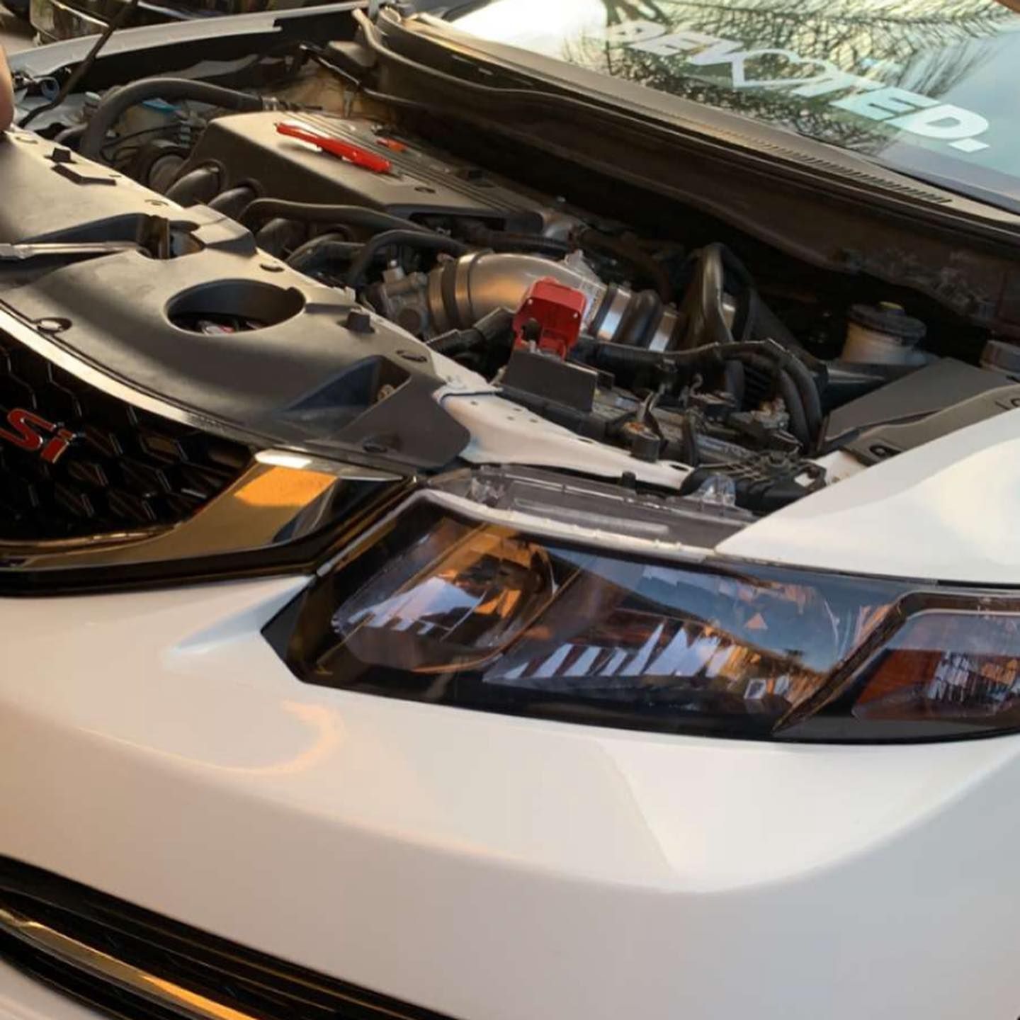 A white car with the hood open and the engine visible