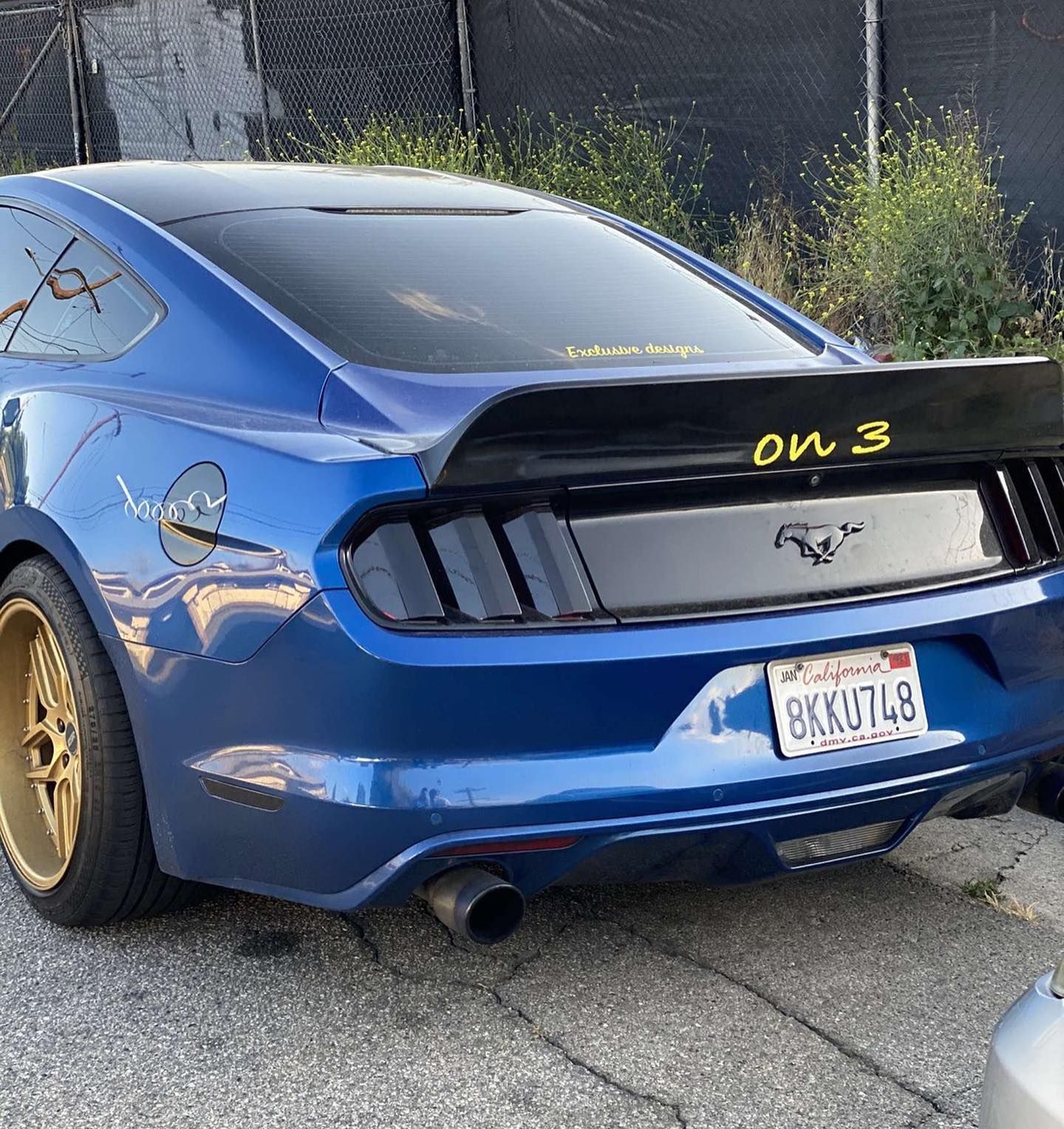 A blue mustang is parked on the side of the road.