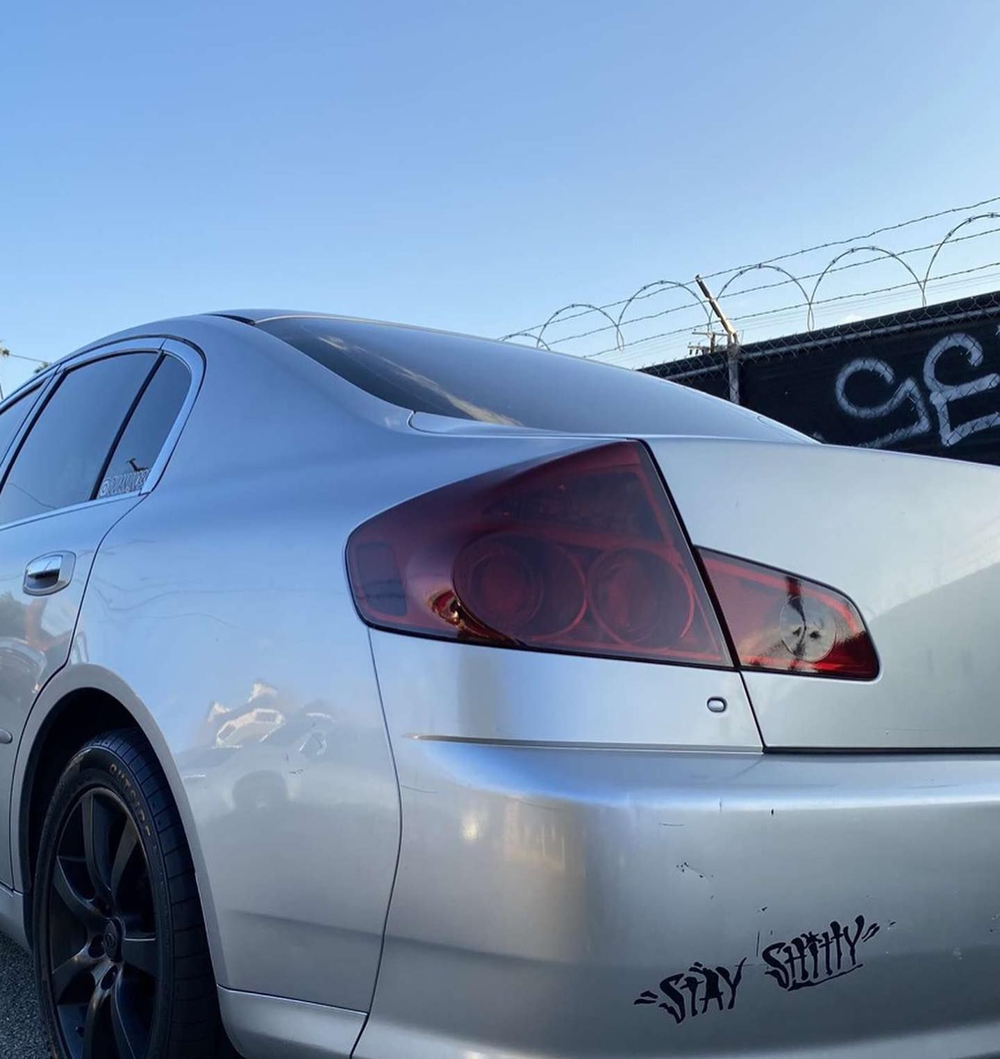 A silver car with a sticker on the back that says stay smiley