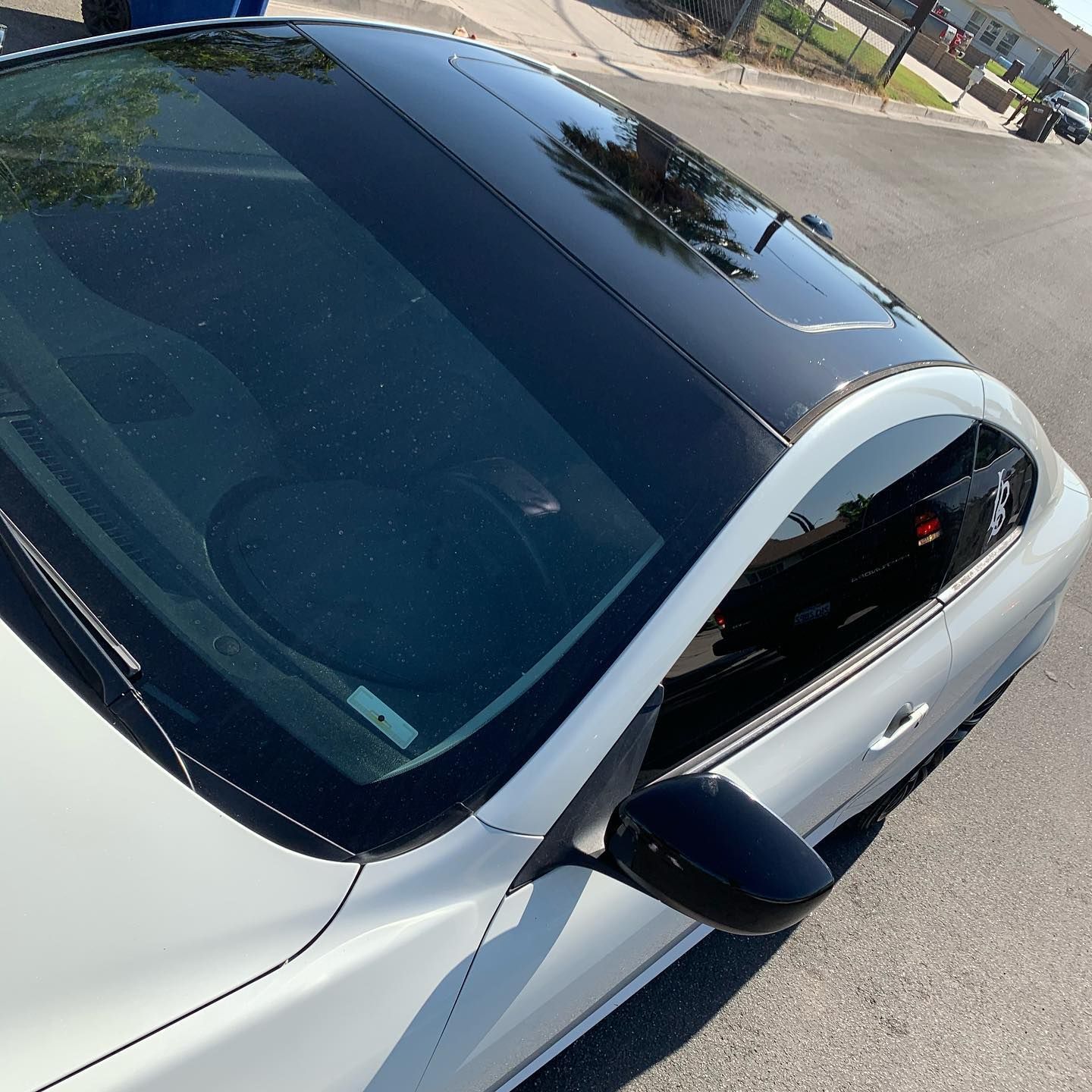 A white car with a black roof is parked on the street