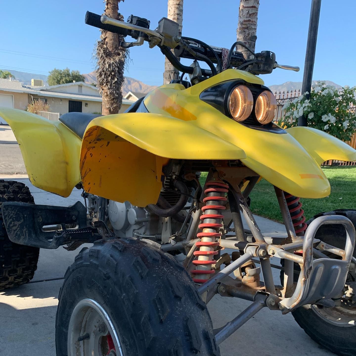 A yellow atv is parked on the side of the road