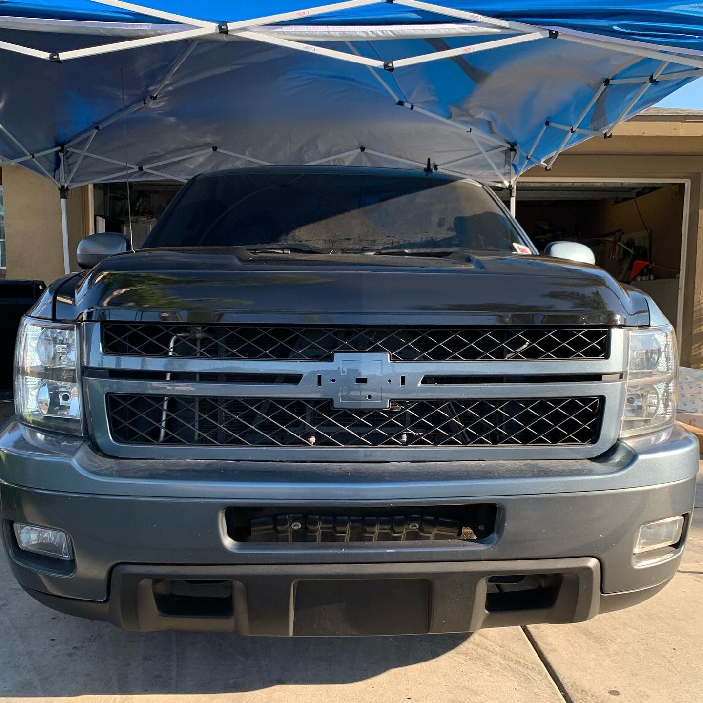 A chevrolet truck is parked under a blue canopy