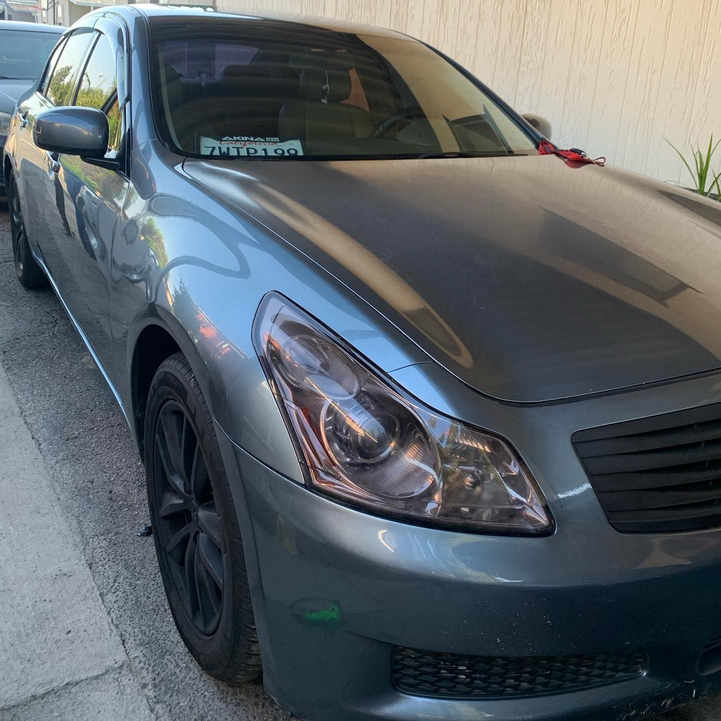 A gray car is parked in front of a white wall