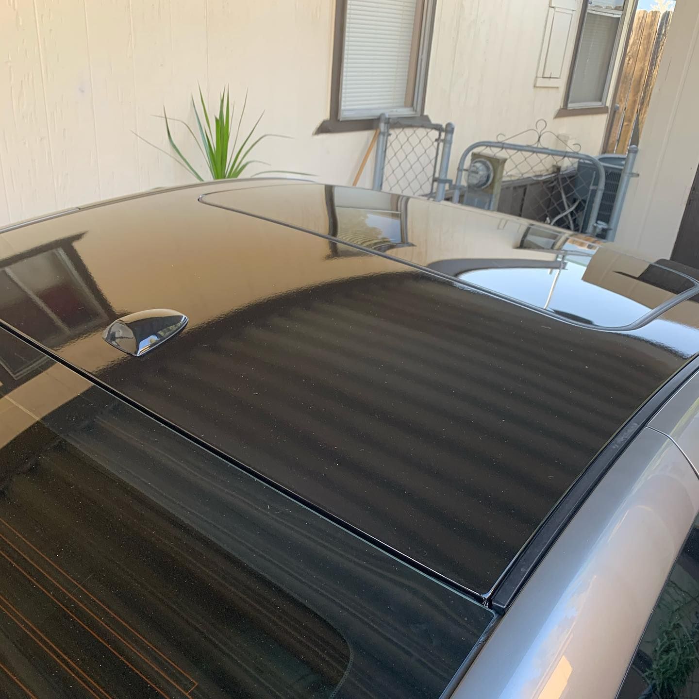 A black car with a roof antenna is parked in front of a house.