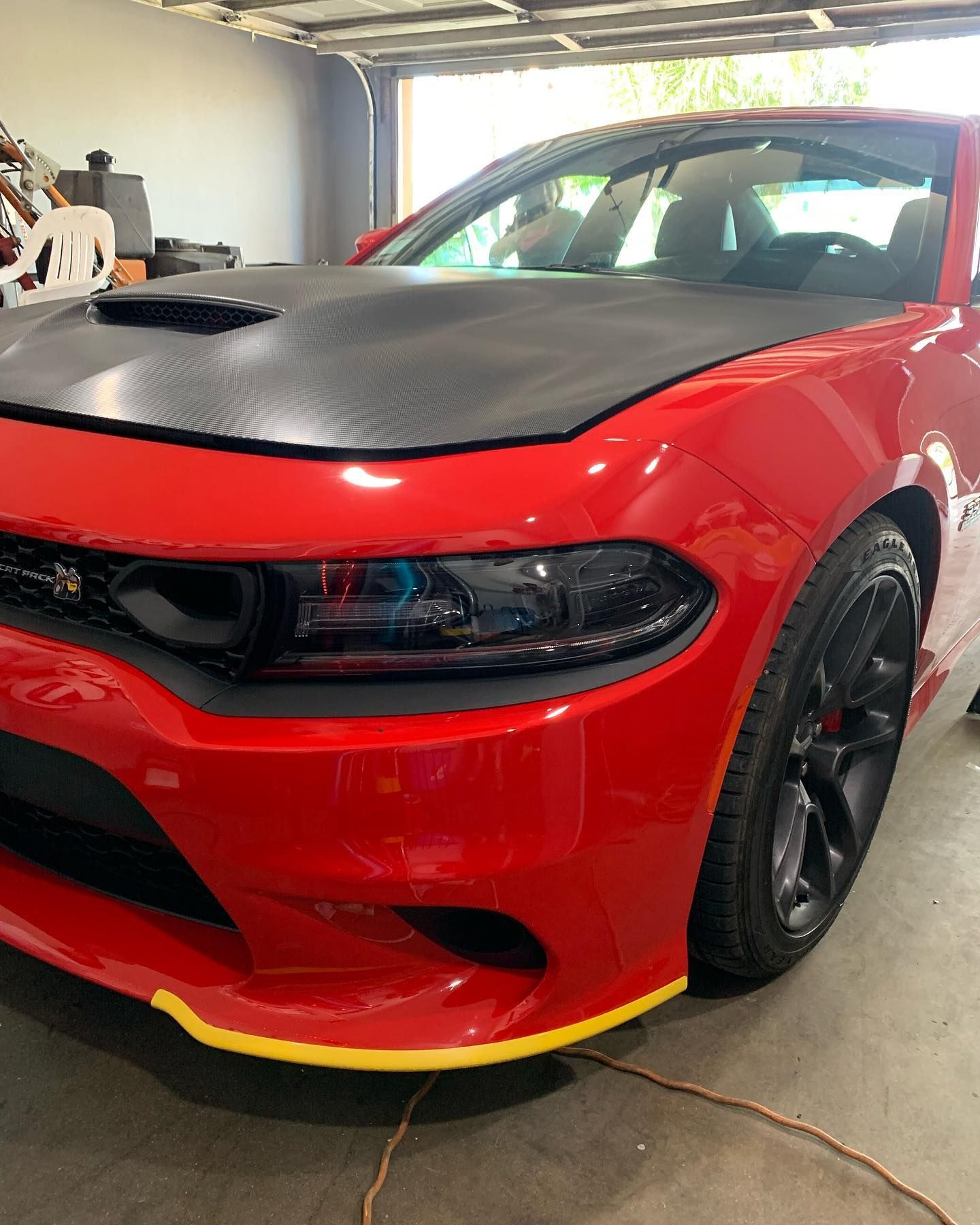 A red dodge charger is parked in a garage.