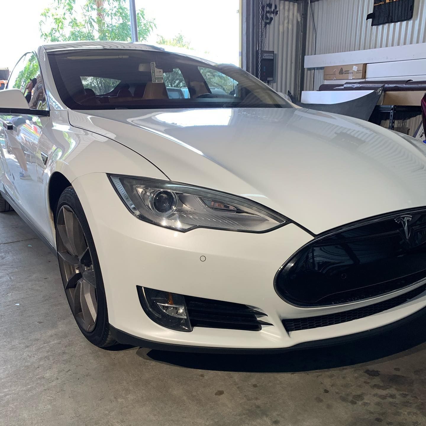 A white tesla model s is parked in a garage