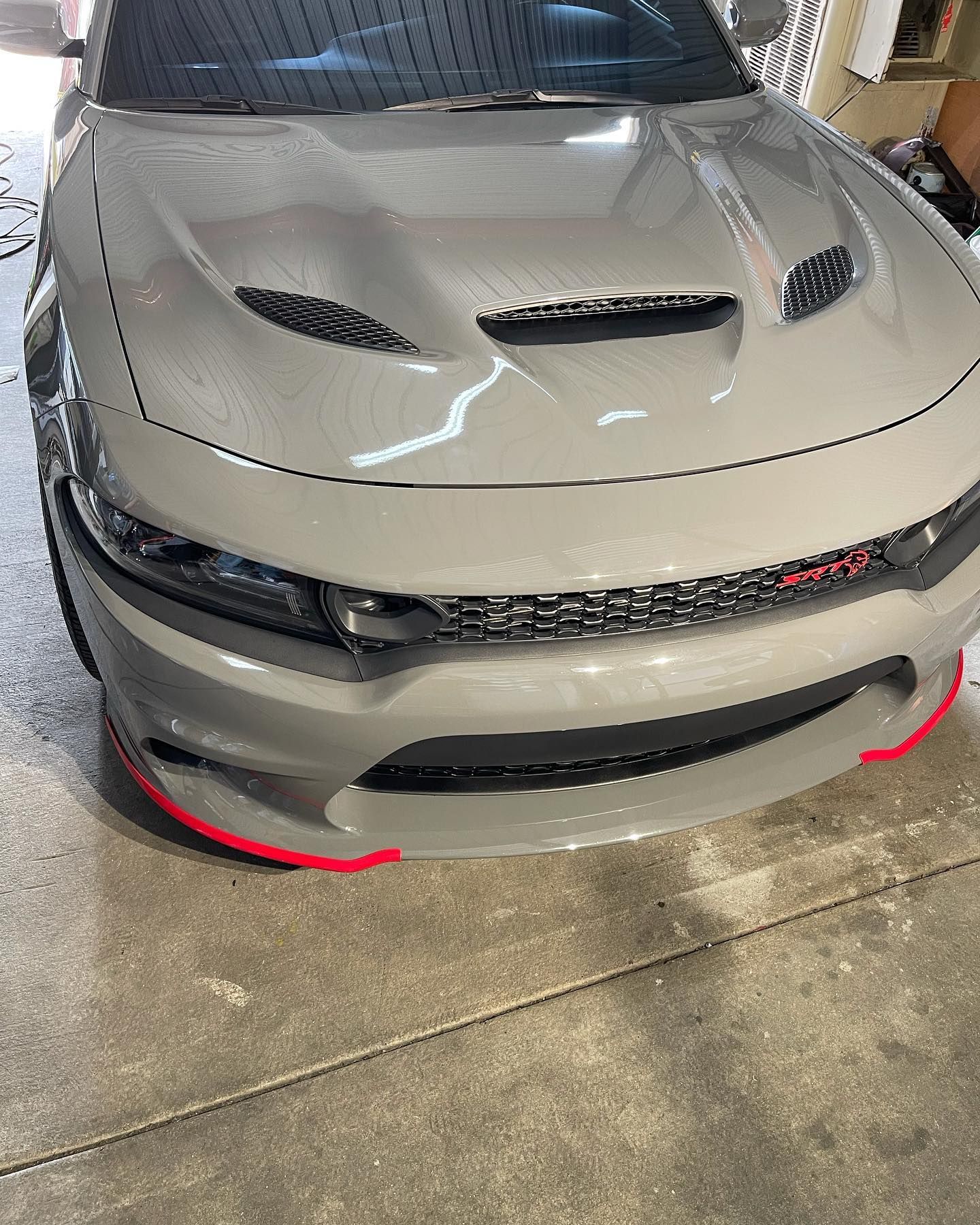 A gray dodge charger is parked in a garage.