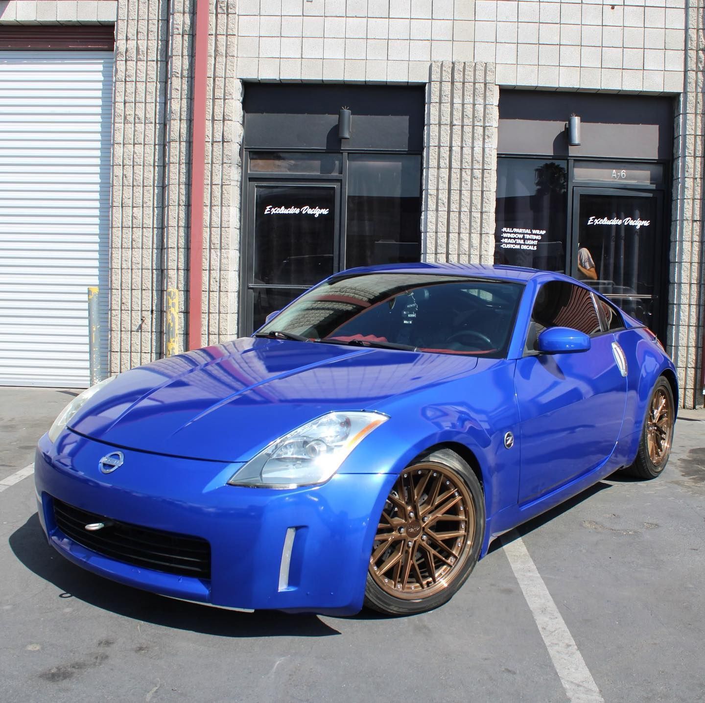 A blue nissan sports car is parked in front of a building