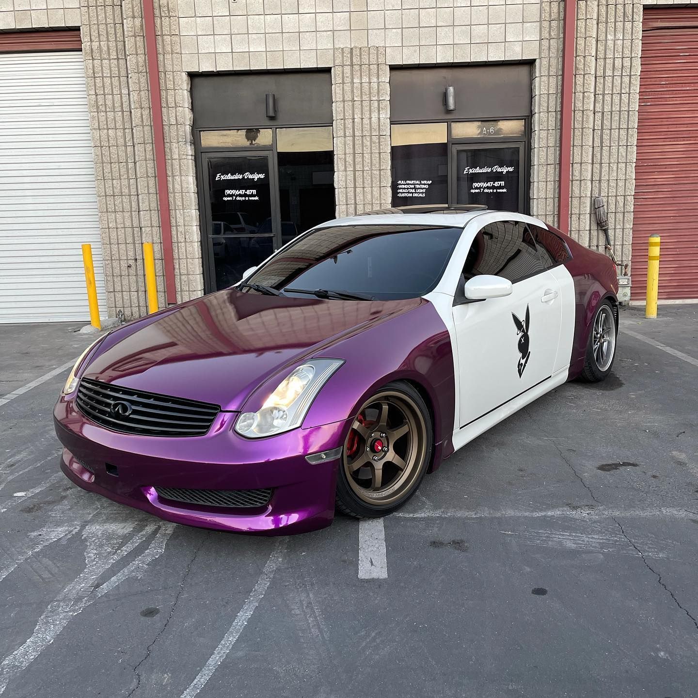 A purple and white car is parked in front of a building