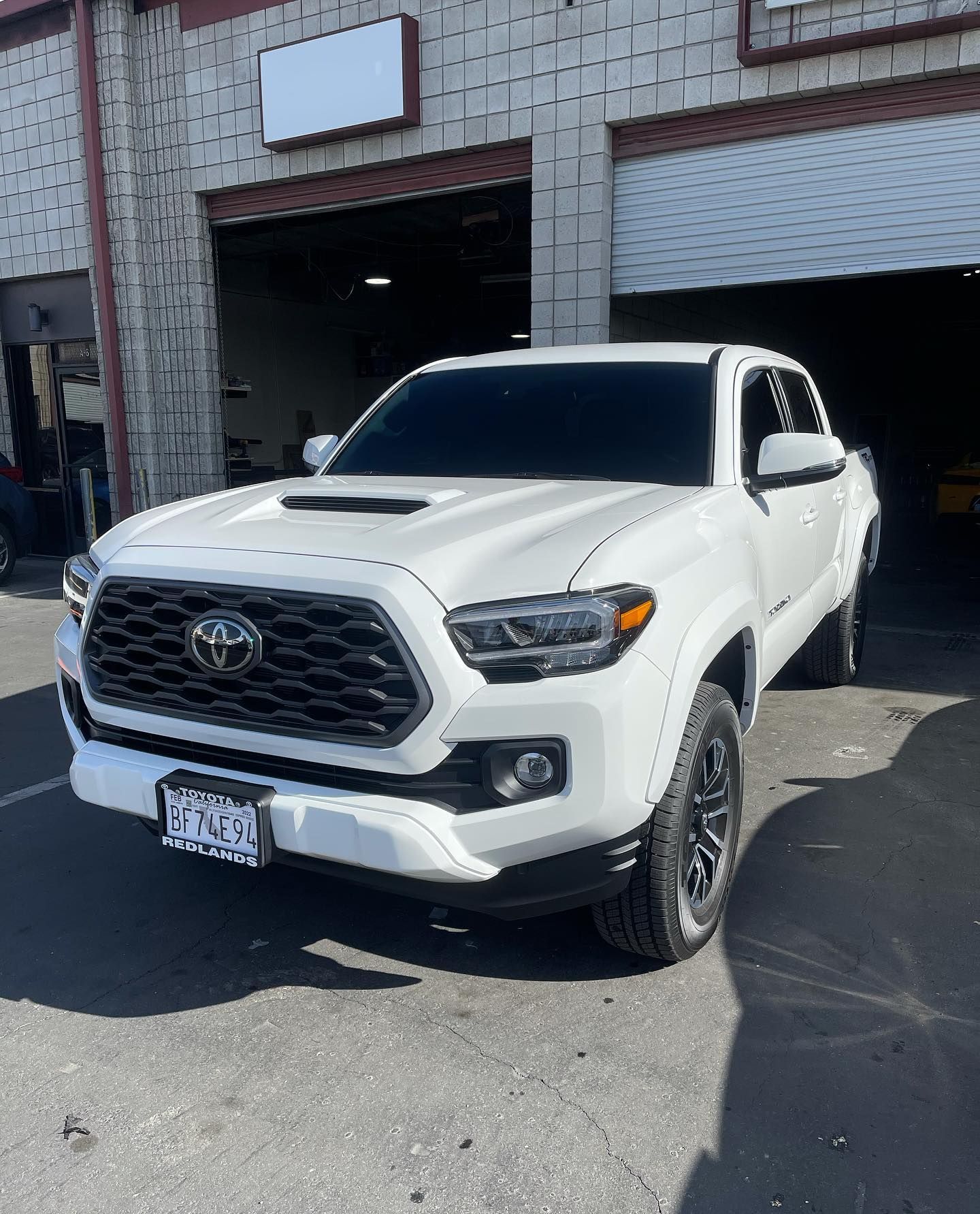 A white toyota tacoma is parked in front of a garage.