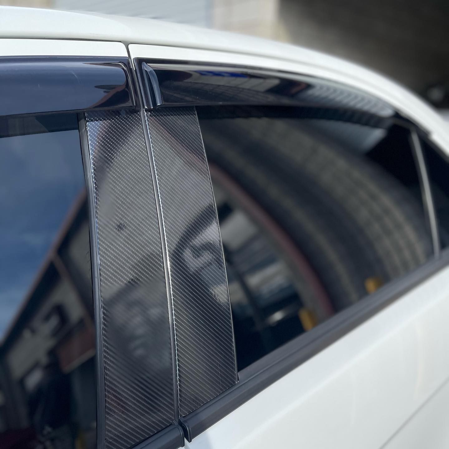 A white car with a reflection of a building in the window