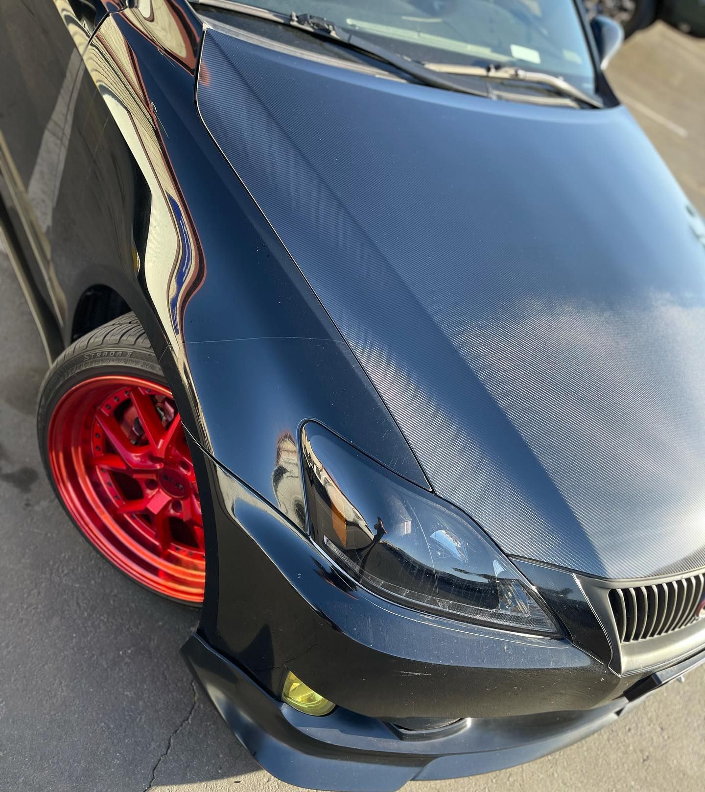 A black car with red wheels is parked on the side of the road