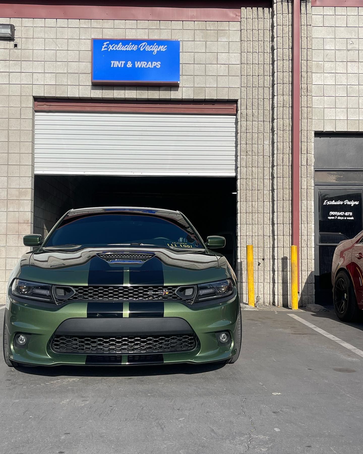 A green car is parked in front of a garage door.