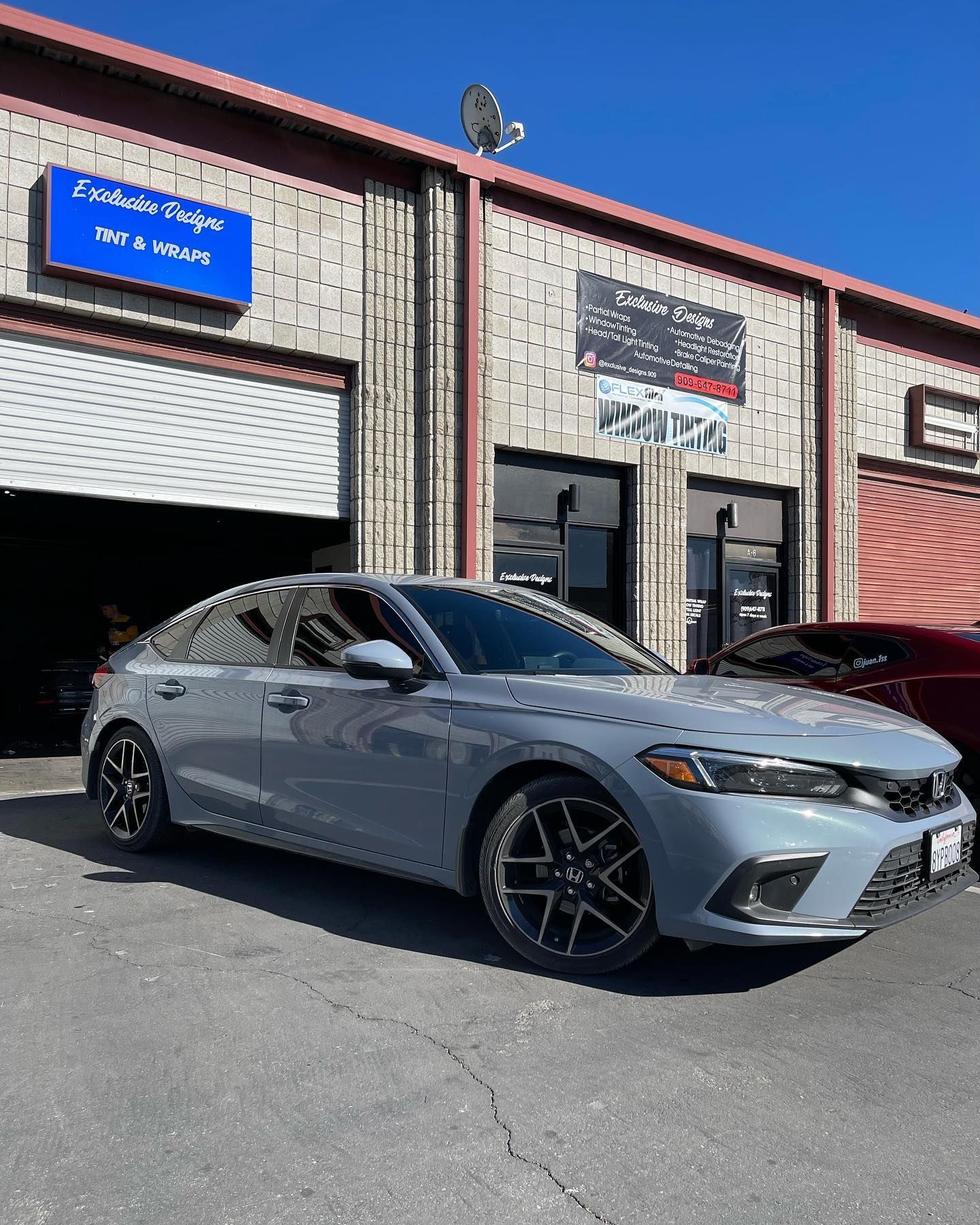A gray honda civic is parked in front of a garage.