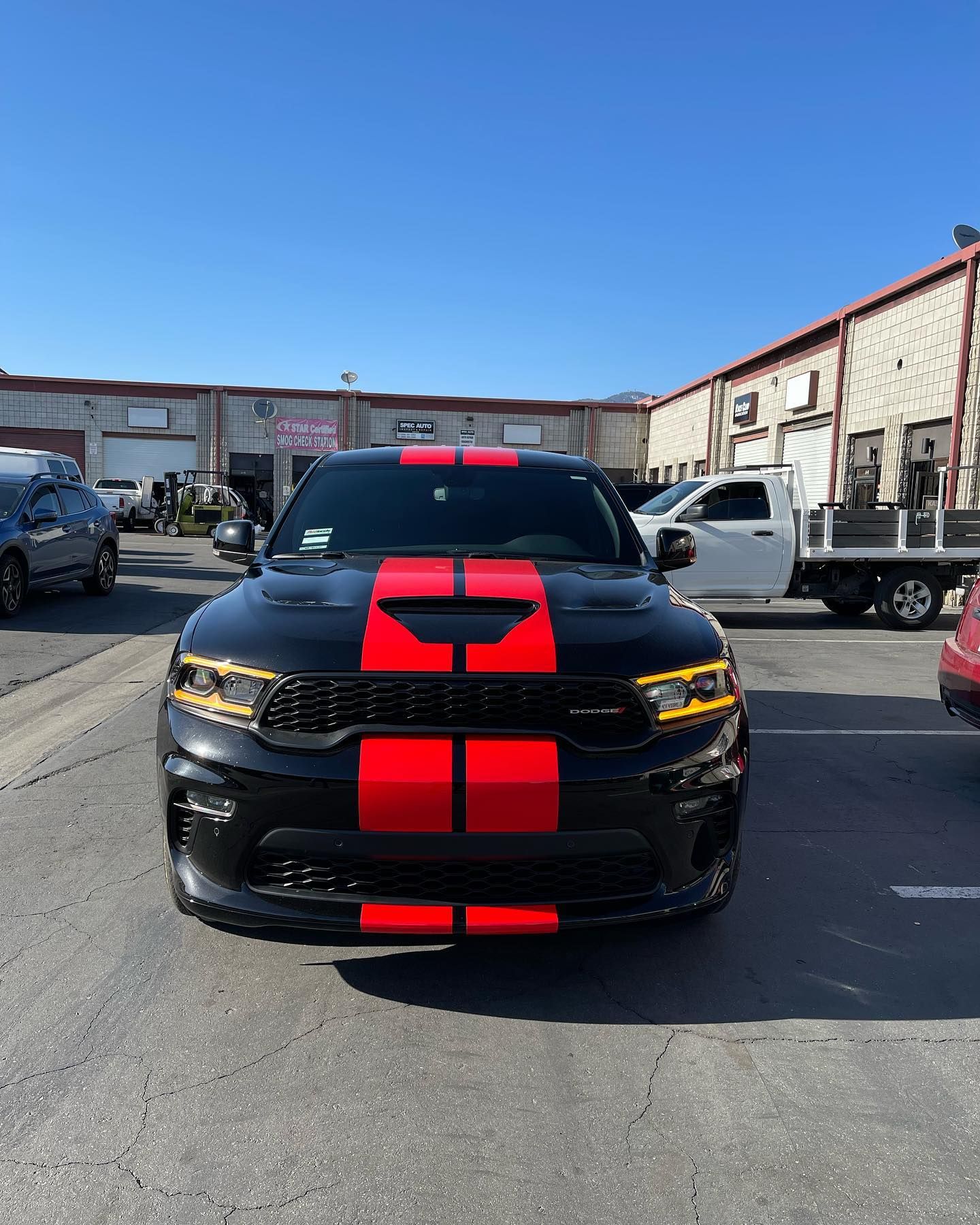 A black car with red stripes on the front is parked in a parking lot.