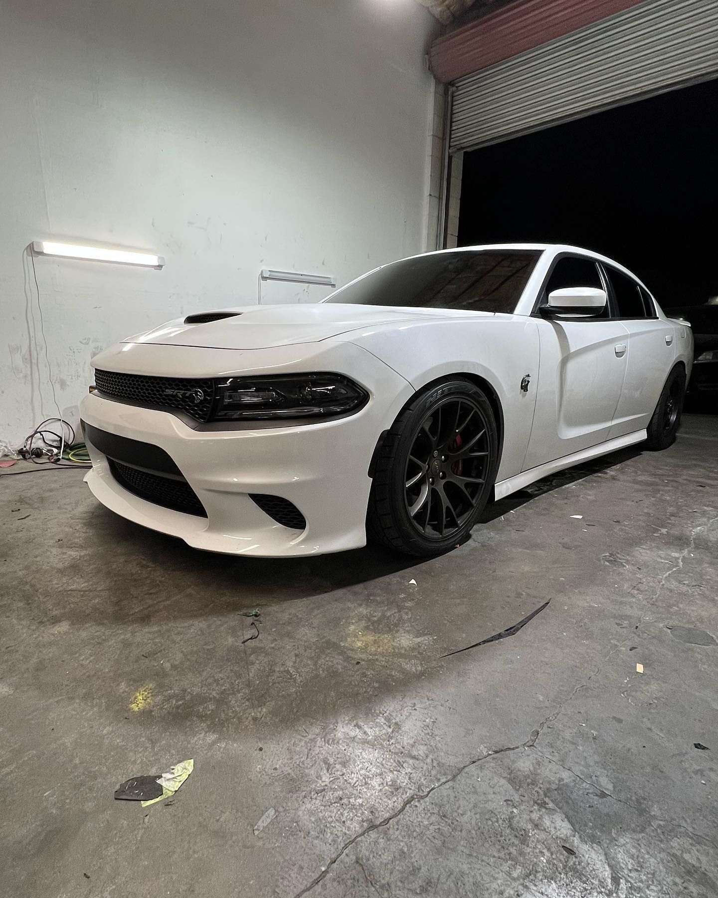 A white dodge charger is parked in a garage.