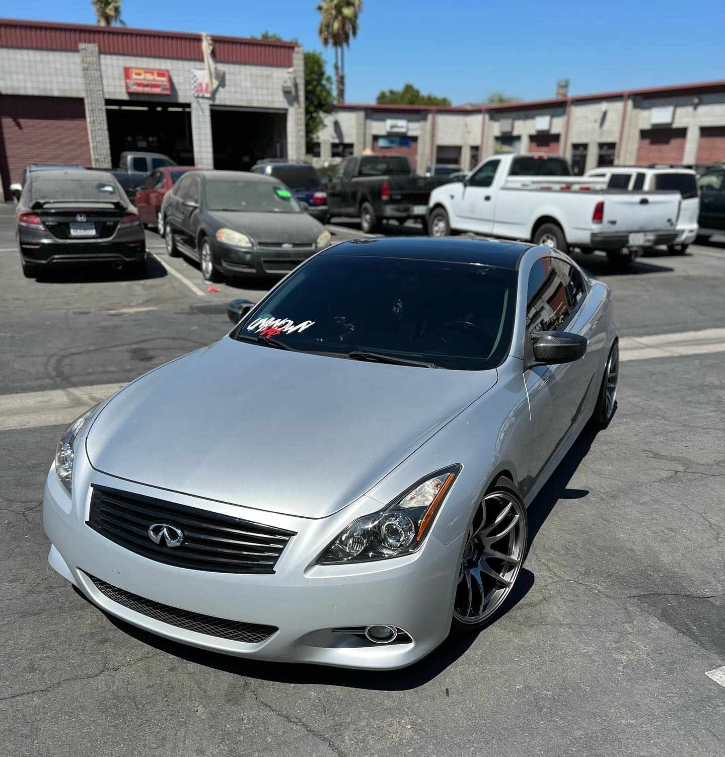 A silver infiniti is parked in a parking lot