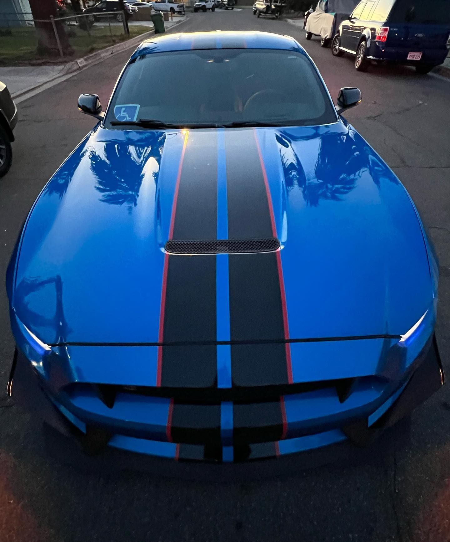 A blue car with black and red stripes on the hood