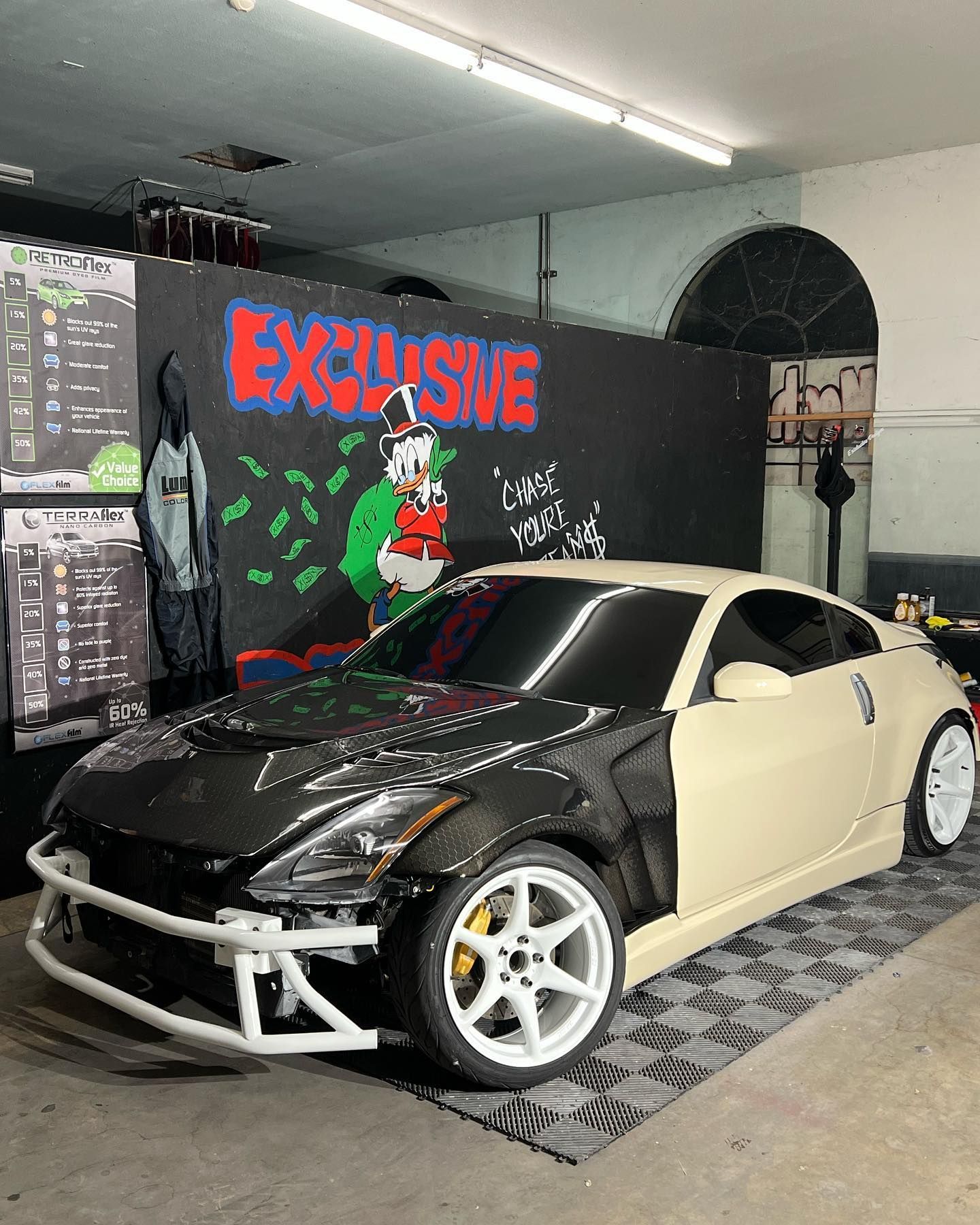 A car is parked in a garage in front of a wall that says exclusive.