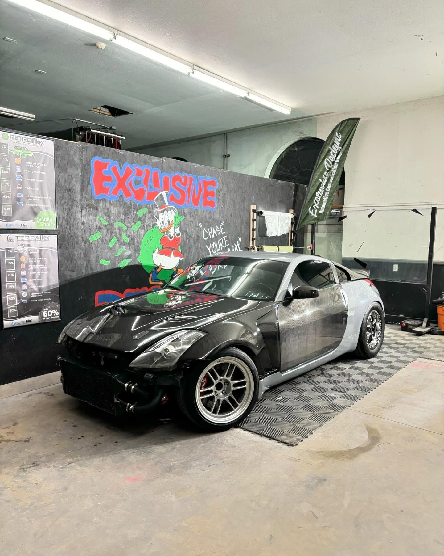 A black car is parked in a garage next to a wall.