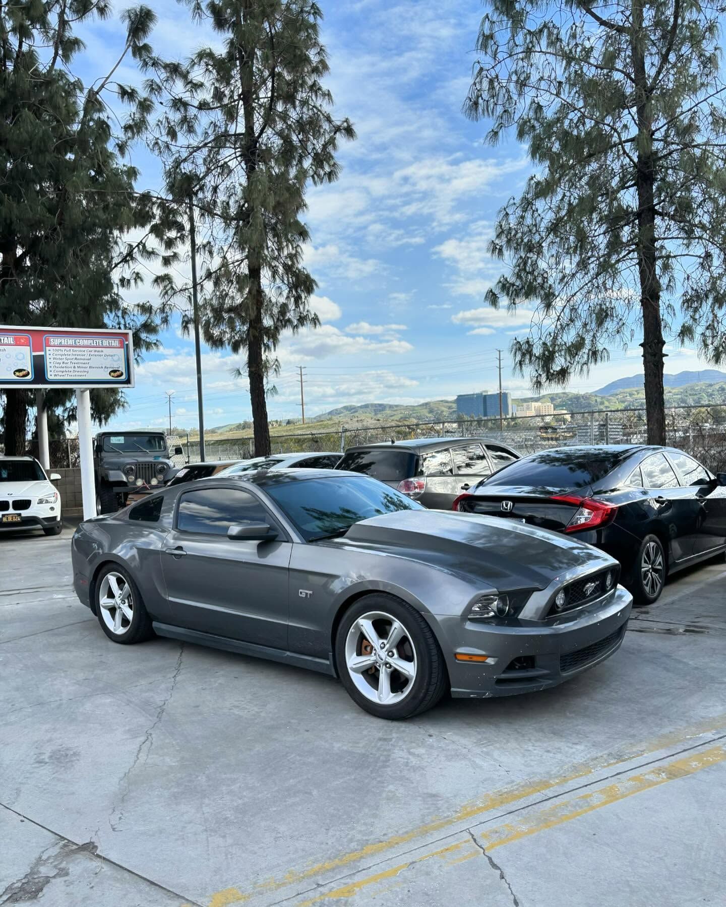 A gray mustang is parked in a parking lot.