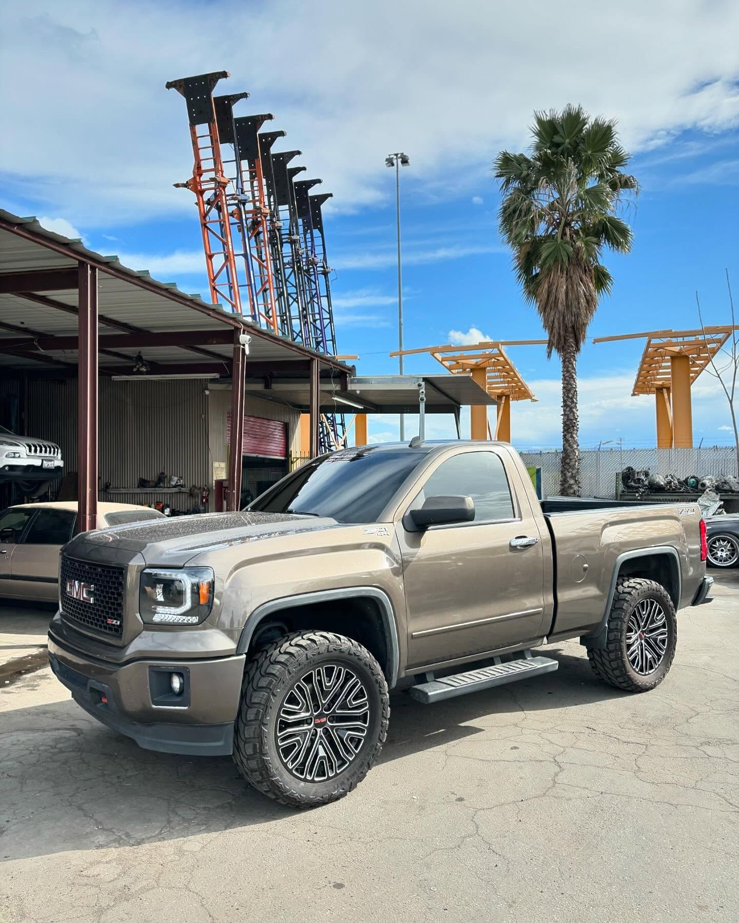 A gmc truck is parked in a parking lot in front of a building.