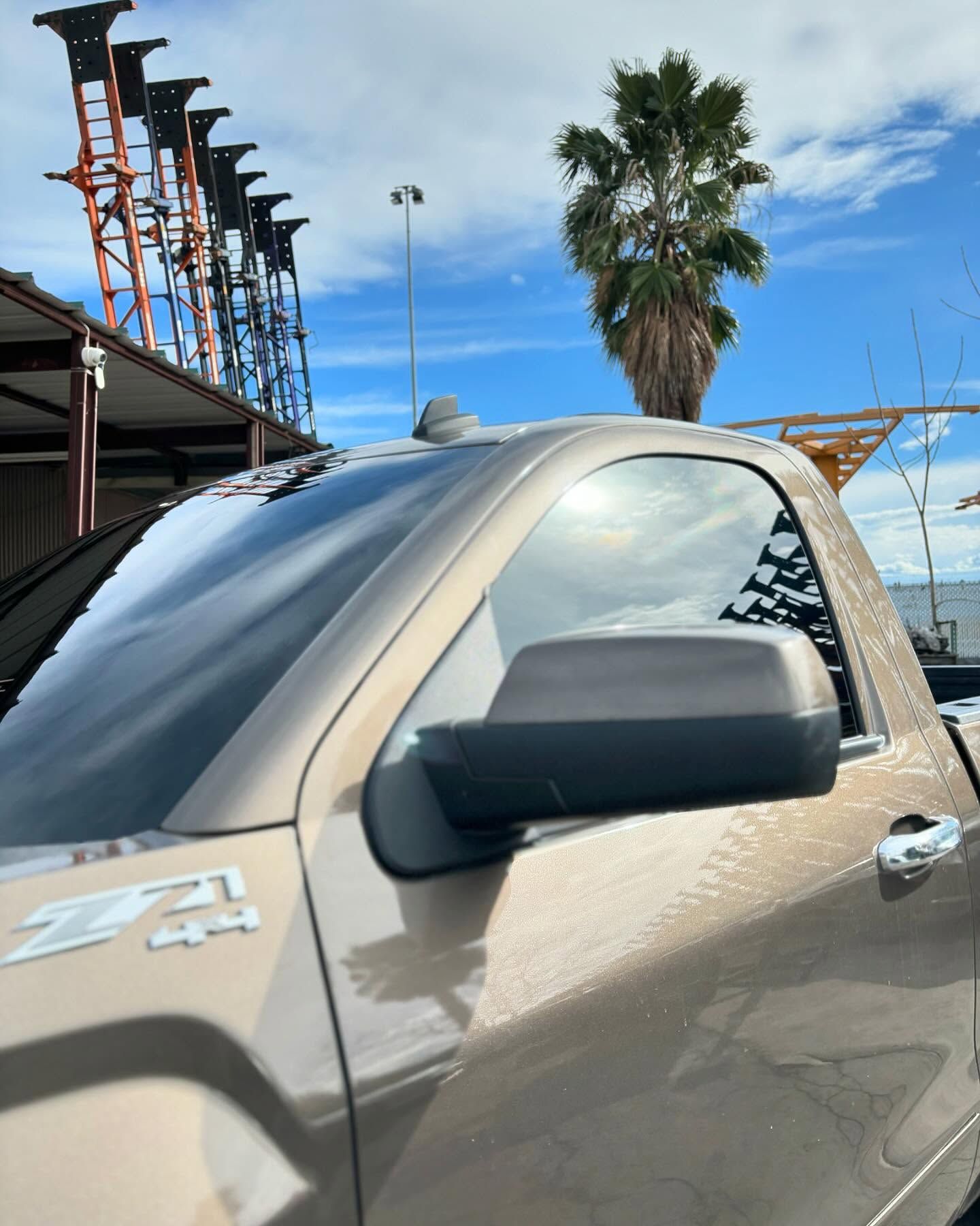 A truck is parked in front of a building with a palm tree in the background
