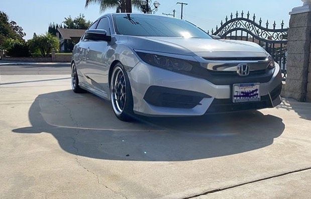 A silver honda civic is parked in a driveway.