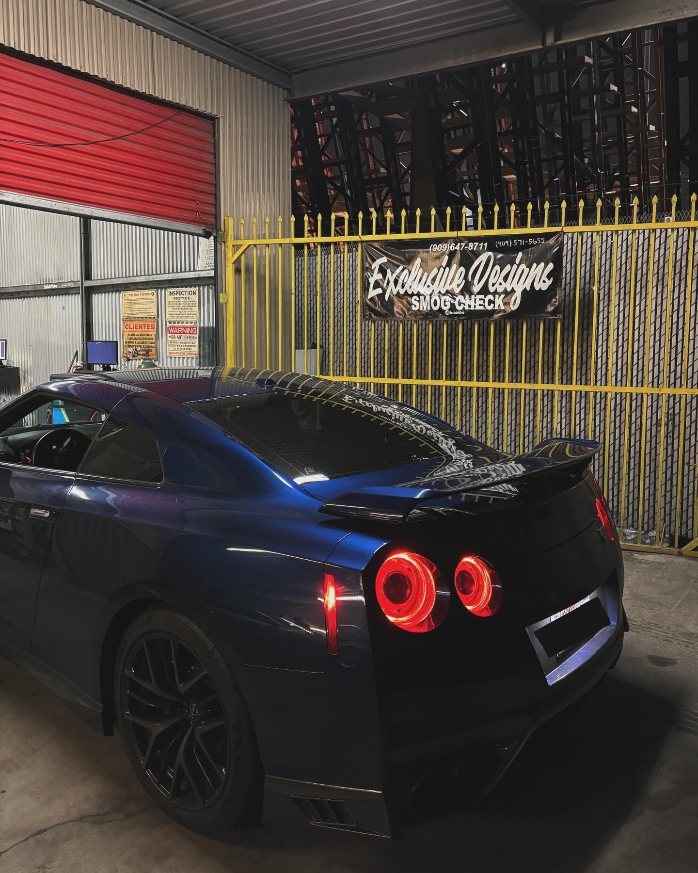 A blue car is parked in front of a sign that says exclusive designs