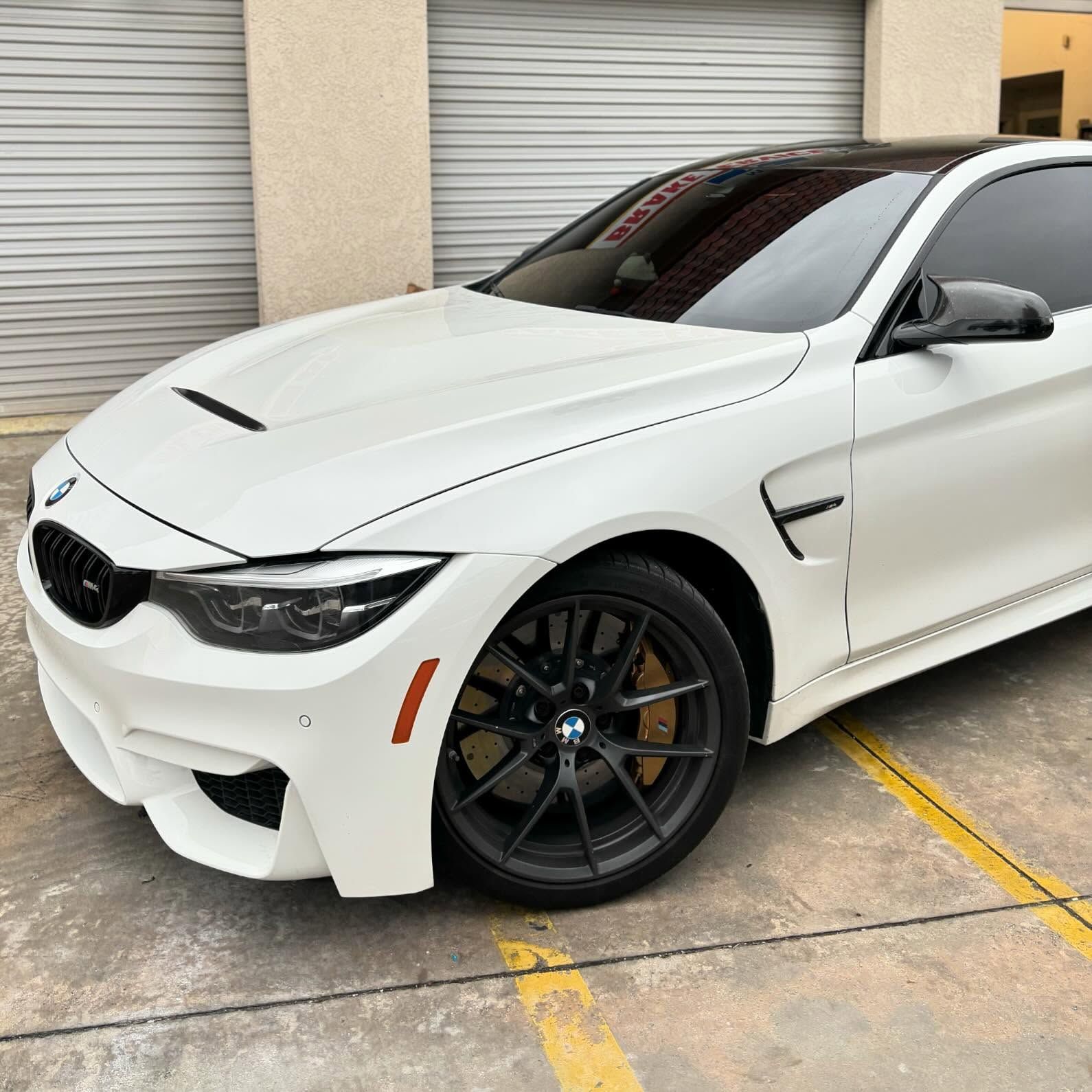 A white bmw m4 is parked in a parking lot