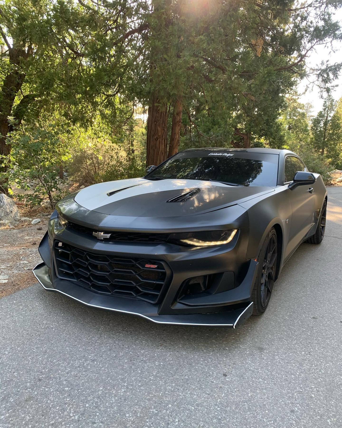 A black and white chevrolet camaro is parked on the side of the road.