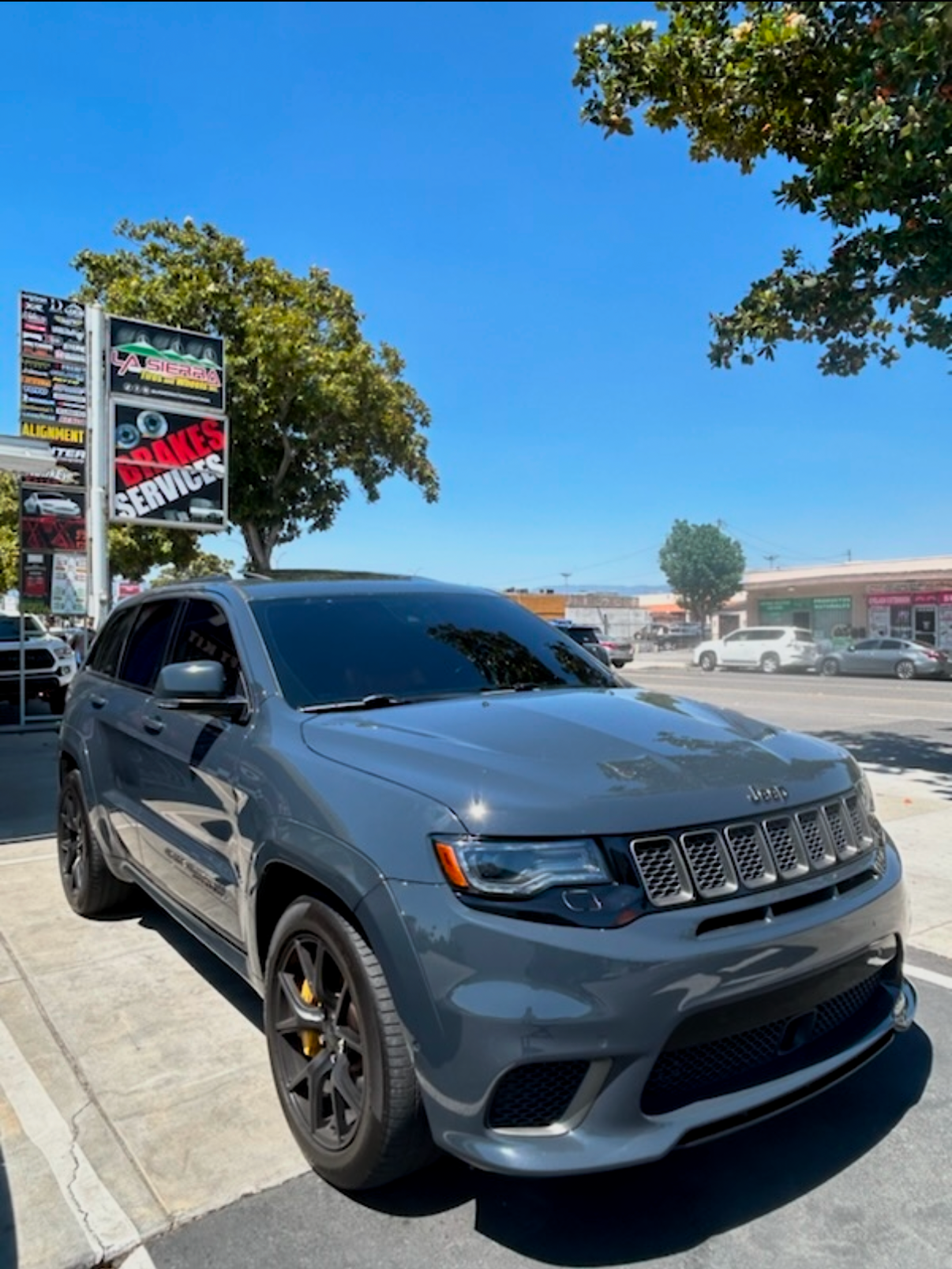 A gray jeep grand cherokee is parked in front of a car wash.