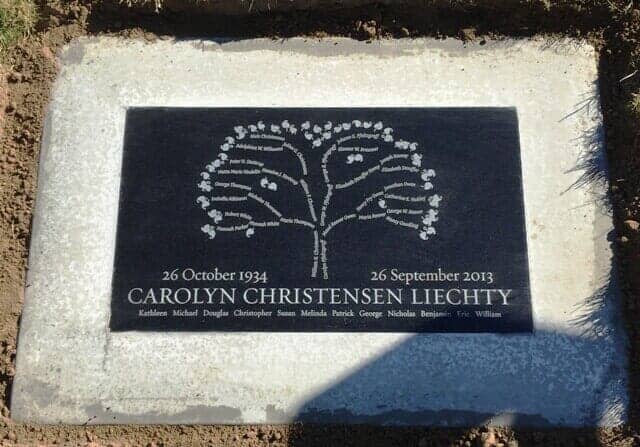 Black memorial plaque with a tree design, surrounded by a gray concrete border.