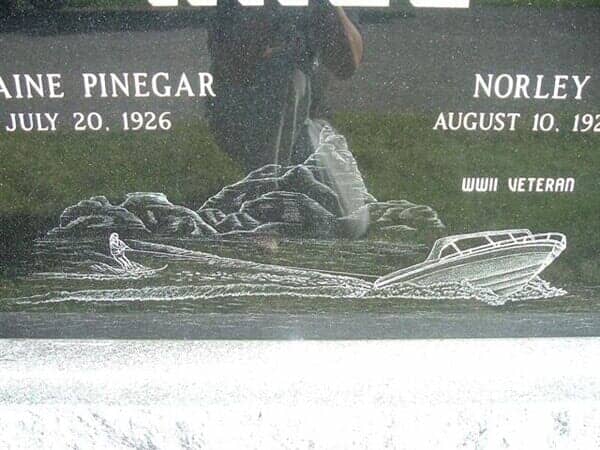 Close-up of a headstone with a boat carving and names: 
