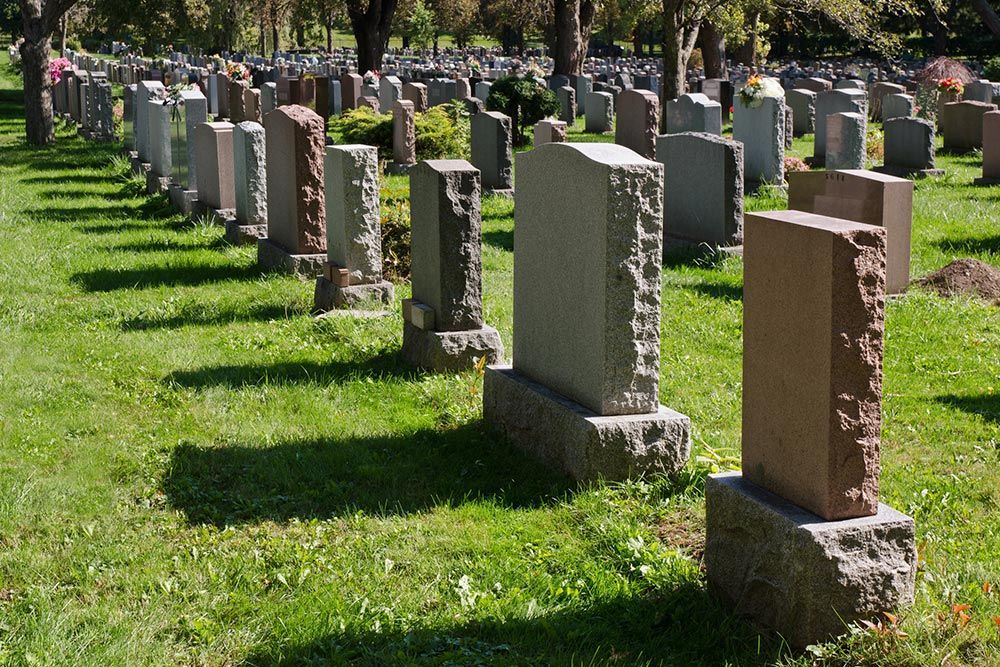 A row of tombstones in a serene cemetery, showcasing custom headstone designs in American Fork, UT.