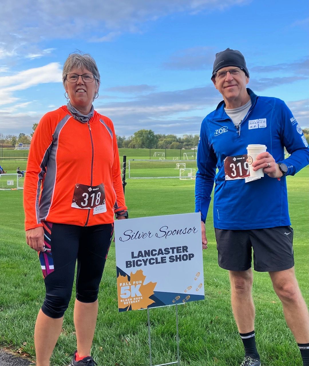 A man and a woman standing next to a sign that says lancaster bicycle shop