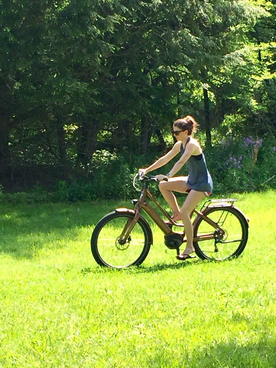 A woman is riding an electric bike on a lush green field.