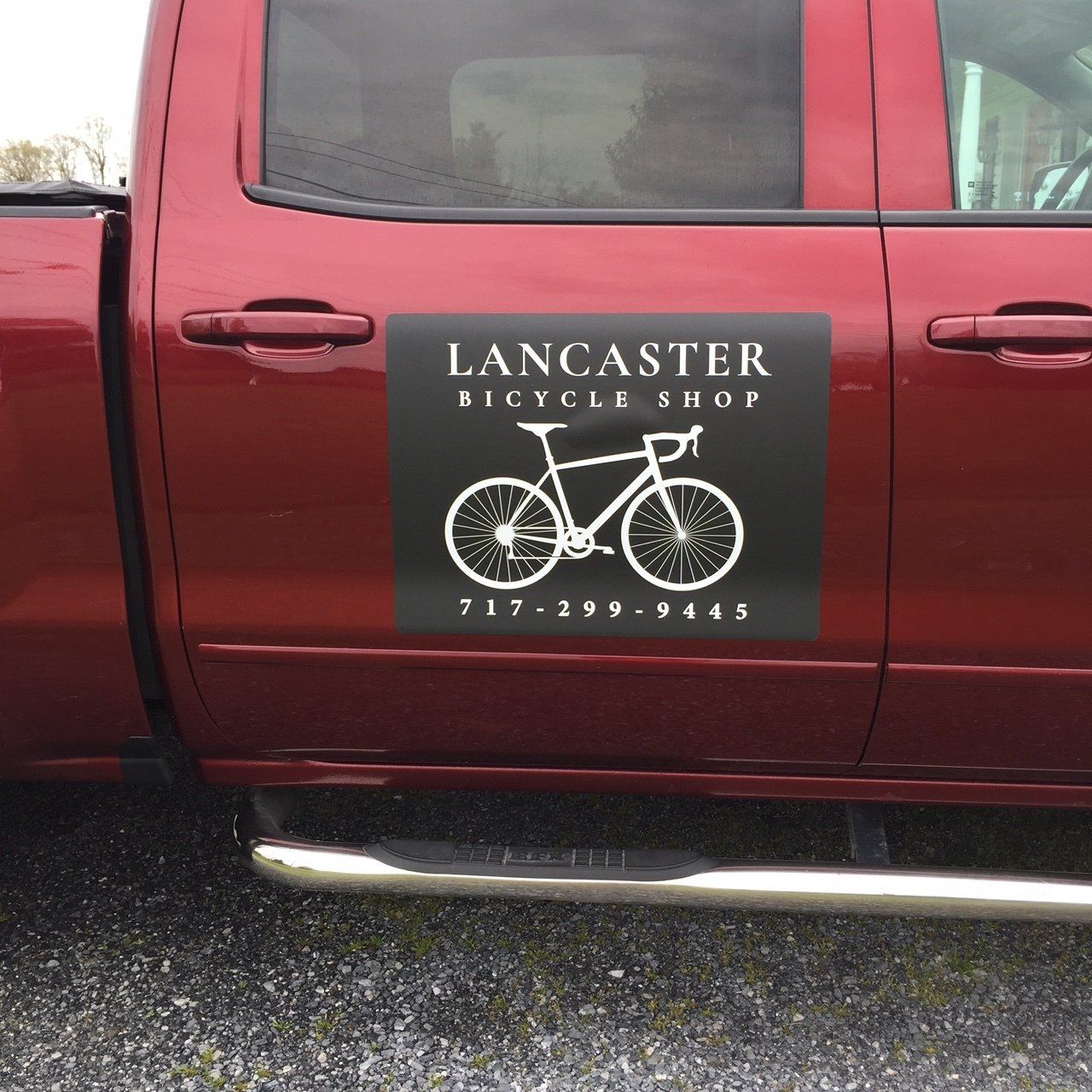 A red truck with a lancaster bicycle shop sticker on the side