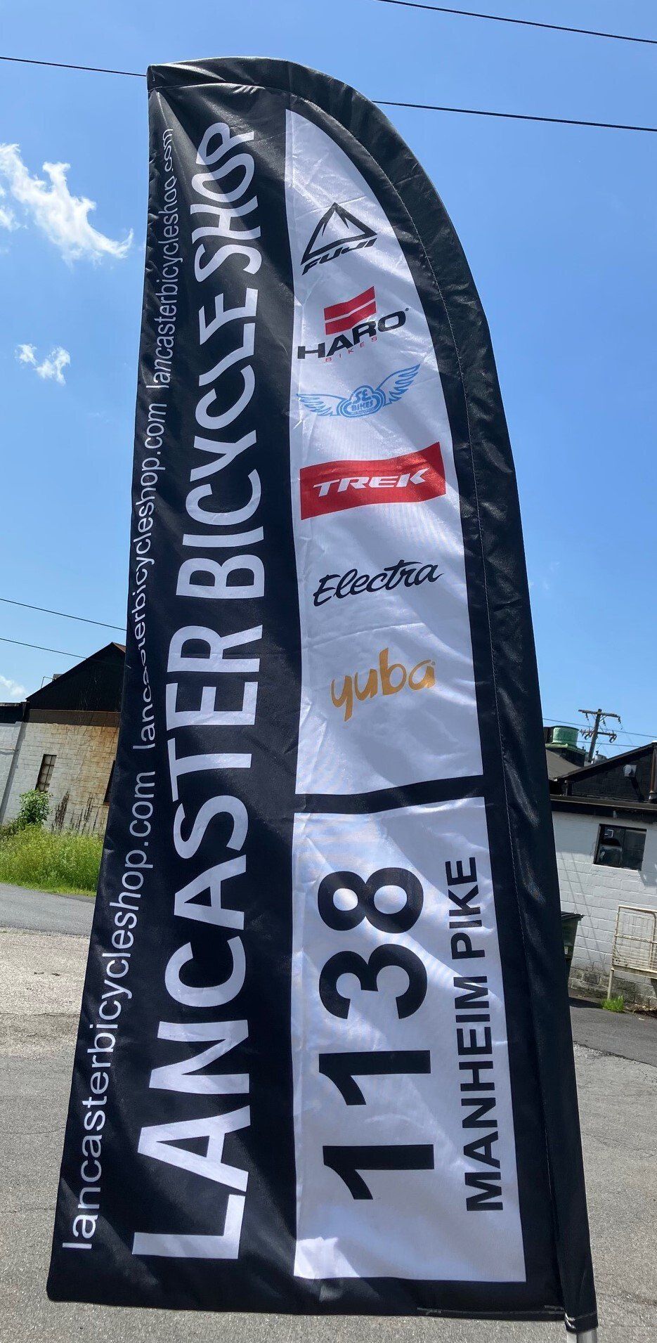 A lancaster bicycle shop flag is sitting on the side of the road.