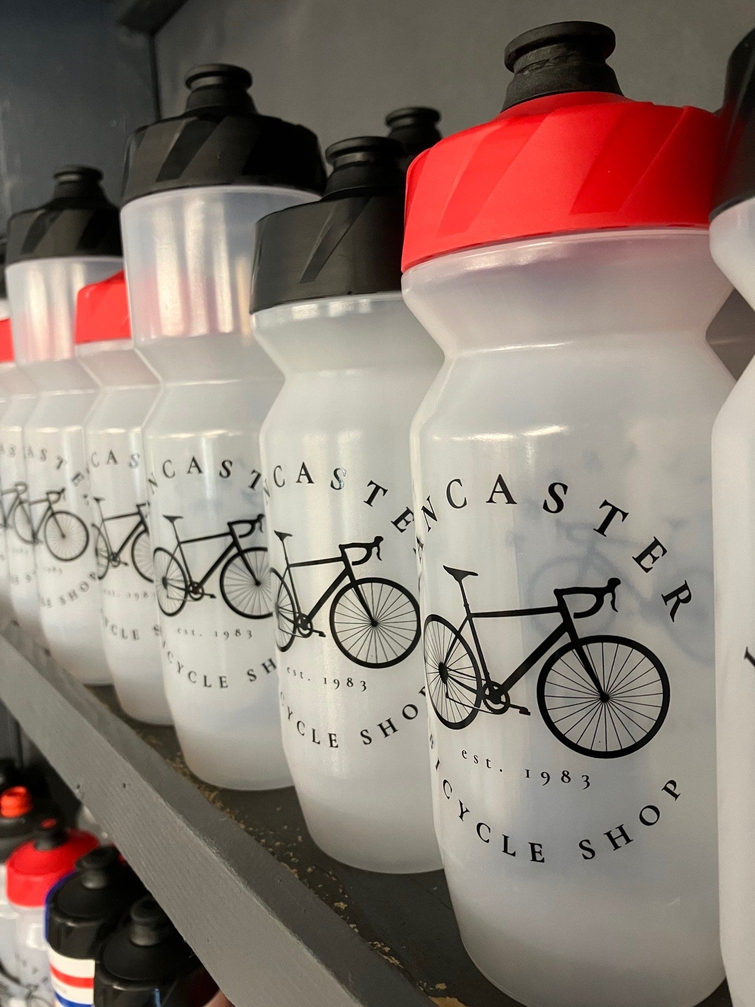 A row of water bottles with a bicycle shop logo on them