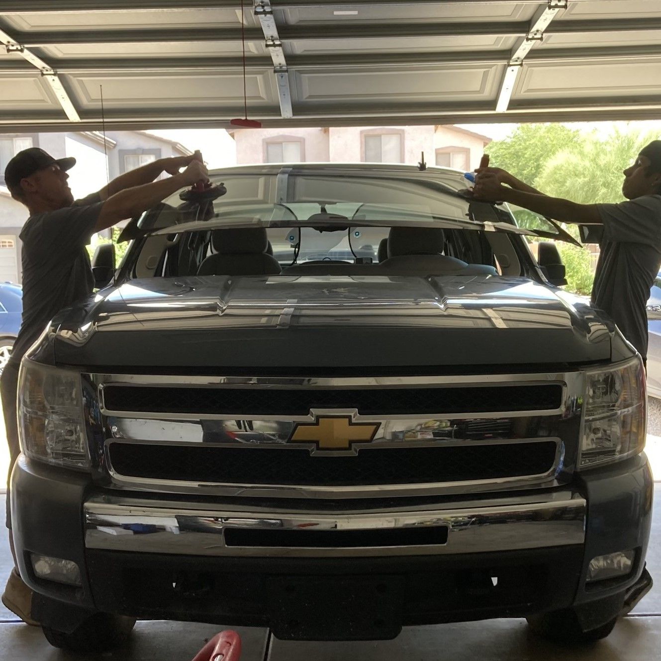 Windshield replacement on a Chevy truck by two auto glass installers.