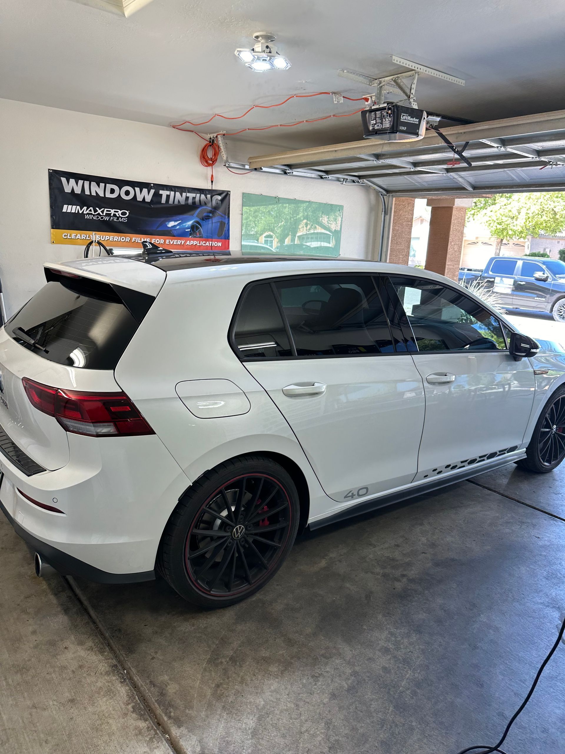 White car in a window tinting shop with dark ceramic window tint installed.
