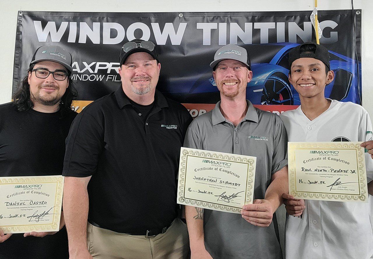 Certified window tint installers standing in front of a window tinting sign.