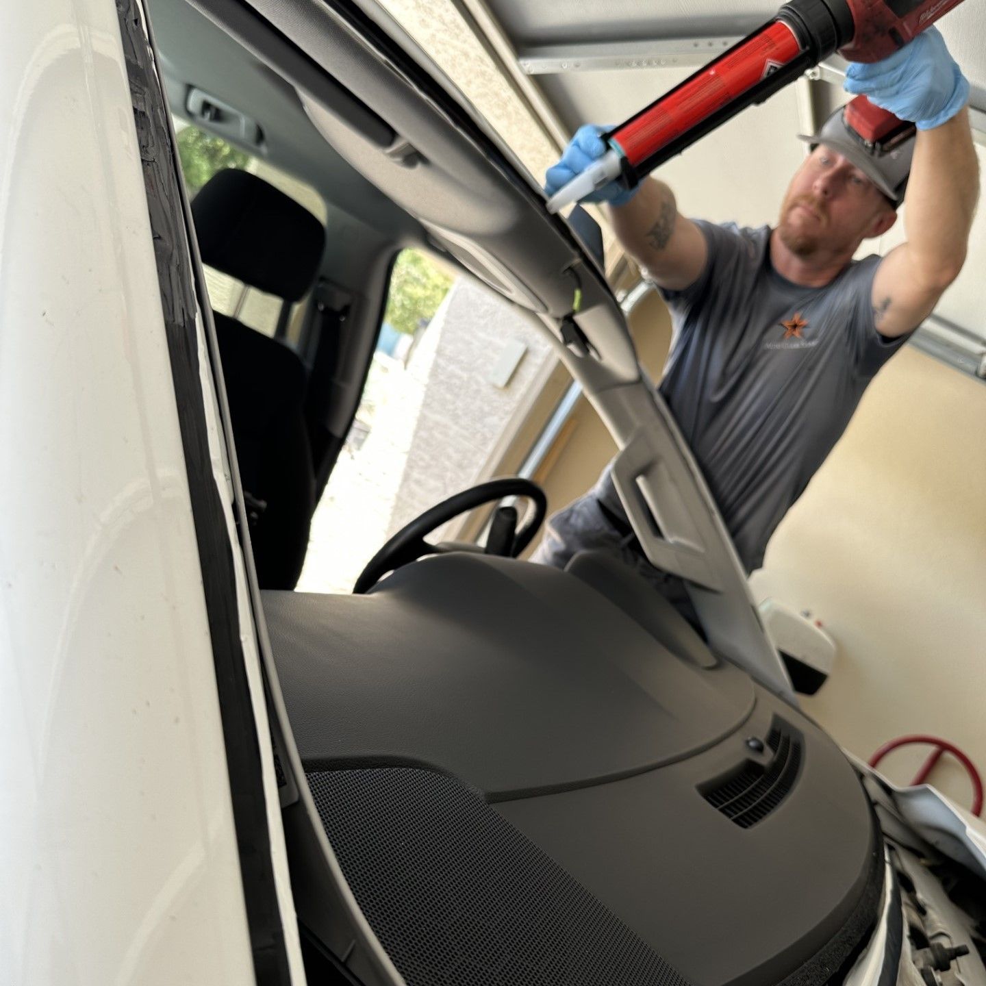 Auto glass installer applying urethane to the body before installing a windshield.