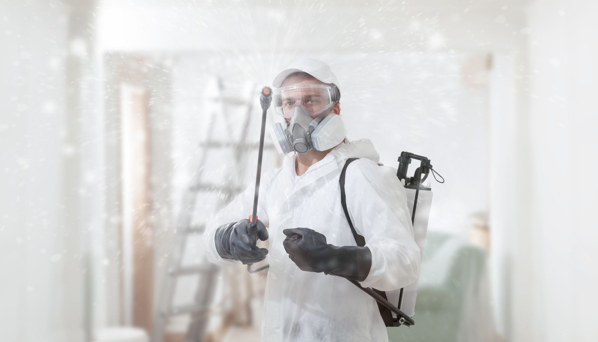 Pest control worker in protective suit spraying a room.