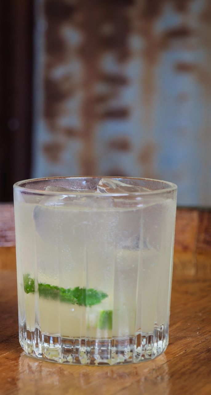 A close up of a drink in a glass on a wooden table.