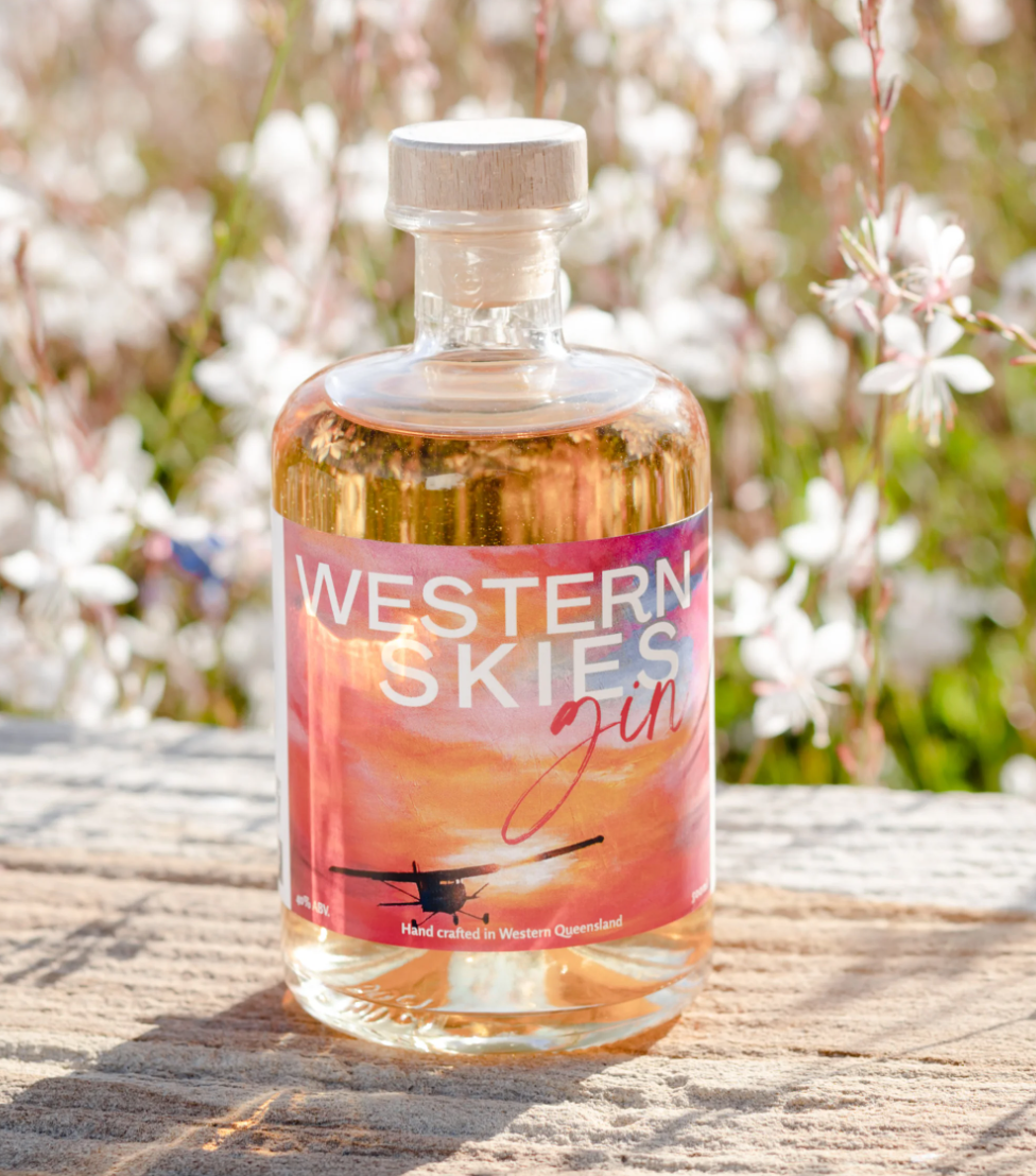 a bottle of western skies gin is sitting on a wooden table .