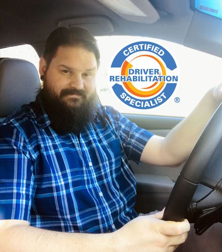 Owner Dustin Abram  sitting in a car with a certified driver rehabilitation specialist logo