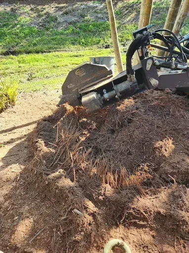 A stump grinder is sitting on top of a pile of dirt.