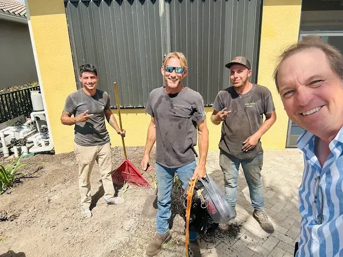 A group of men are standing in front of a yellow building.